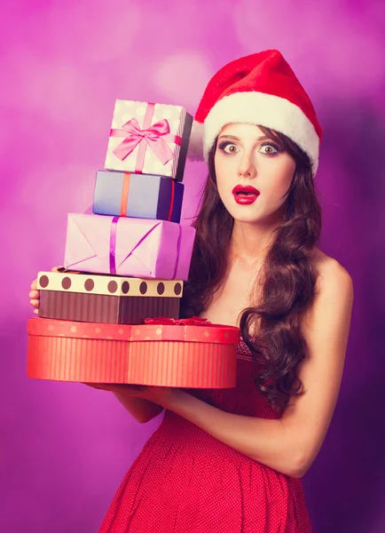 Beautiful brunette girl in christmas hat with gifts  on violet b — Stock Photo, Image