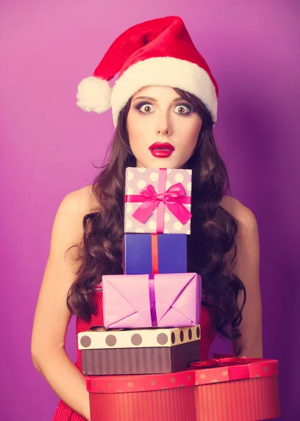 Hermosa chica morena en sombrero de Navidad con regalos en violeta b —  Fotos de Stock