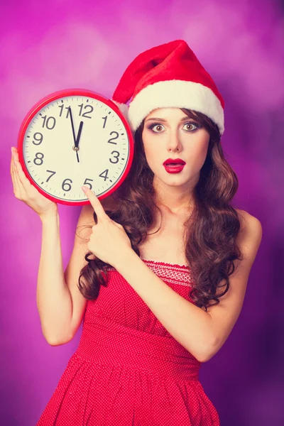 Bella ragazza bruna in cappello di Natale con orologio enorme sulla viola — Foto Stock