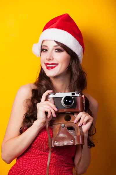 Bella ragazza bruna in cappello di Natale con fotocamera su b giallo — Foto Stock