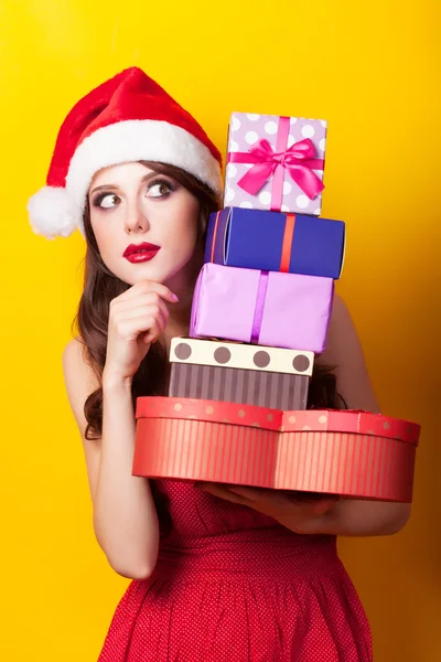 Menina morena bonita em chapéu de Natal com presente no bac amarelo — Fotografia de Stock