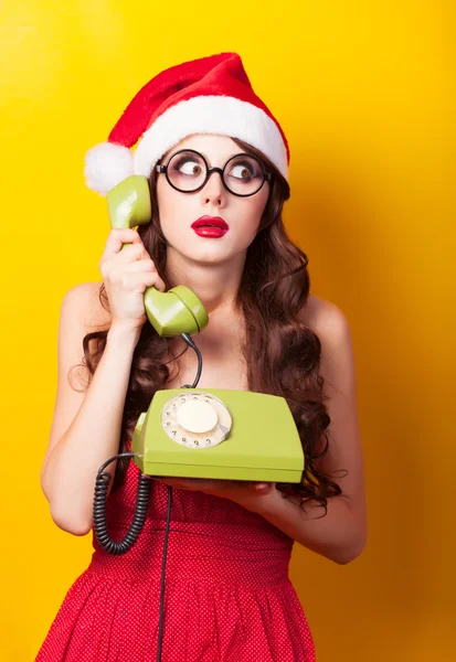 Beautiful brunette girl in christmas hat with telephone on yello — Stock Photo, Image