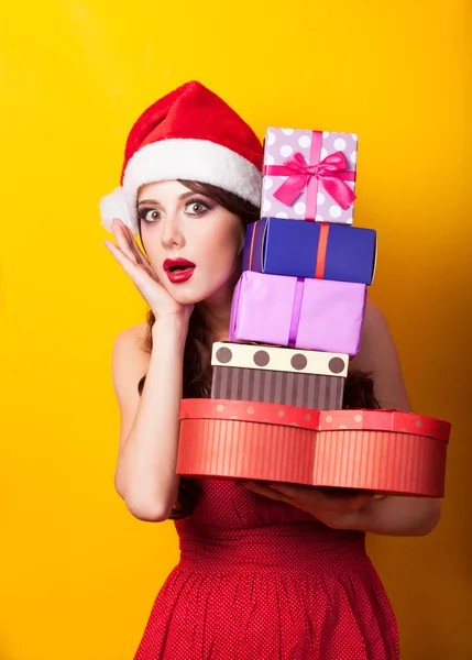 Menina morena bonita em chapéu de Natal com presente no bac amarelo — Fotografia de Stock