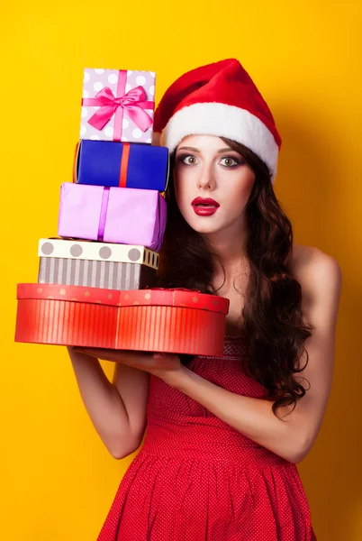 Menina morena bonita em chapéu de Natal com presente no bac amarelo — Fotografia de Stock