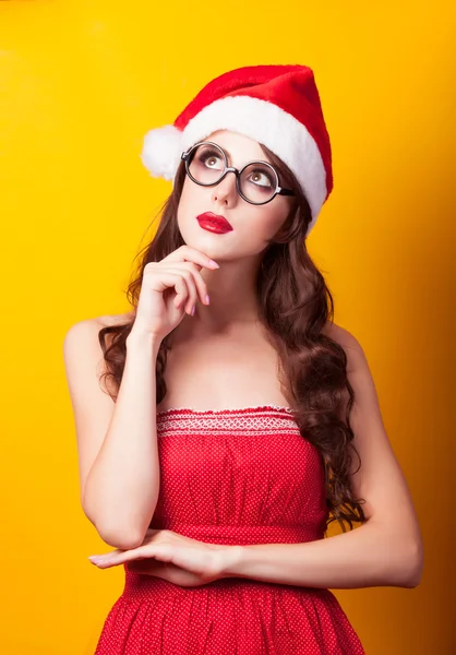 Belle fille brune en chapeau de Noël avec des lunettes sur jaune — Photo