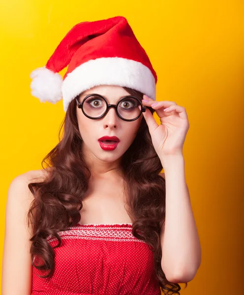 Όμορφη μελαχρινή κοπέλα σε Χριστούγεννα καπέλο με γυαλιά σε κίτρινο — Φωτογραφία Αρχείου