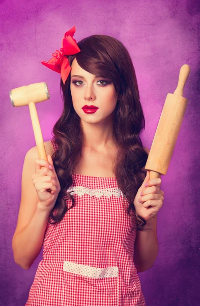 Schöne brünette Hausfrau mit Nudelholz auf violettem Hintergrund — Stockfoto