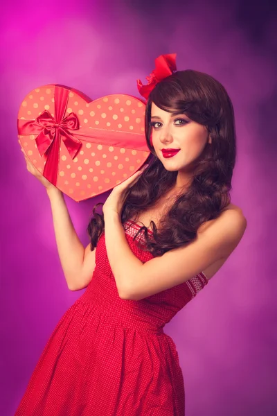 Beautiful brunette girl with heart shape gift on violet backgrou Stock Picture