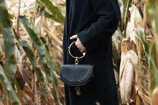 秋のトウモロコシ畑で黒コートのスタイリッシュな女性 — ストック写真