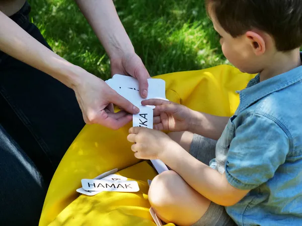 ママは庭で自閉症の子供のためにドマンの技術を使って言葉を発音することを教えてる ロイヤリティフリーのストック画像