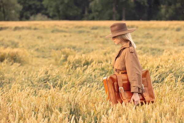 Buğday tarlasında pelerinli ve şapkalı sarışın kadın. 
