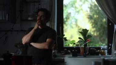 Ev çekimlerinde mutfakta duran düşünceli adam. 