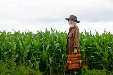 Yazın mısır tarlasında pelerinli ve şapkalı sarışın bir kadın.