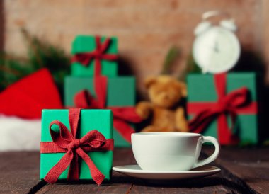 Bir fincan kahve ve Noel hediyeleri ahşap masanın üzerinde..