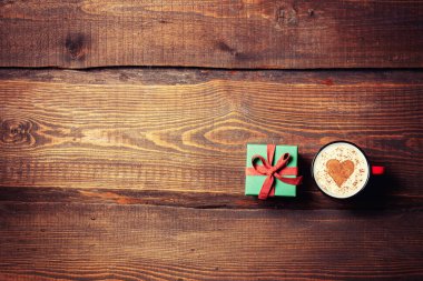 Tahta masadaki hediye kutusunun yanında bir fincan kahve ve kalp şeklinde.. 