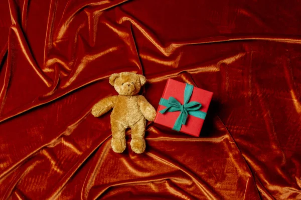 Подарочная Коробка Игрушкой Плюшевого Мишки Фоне Багрового Красного Цвета Ткани — стоковое фото