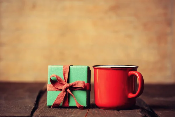 Cup of coffee and gift box on wooden table.