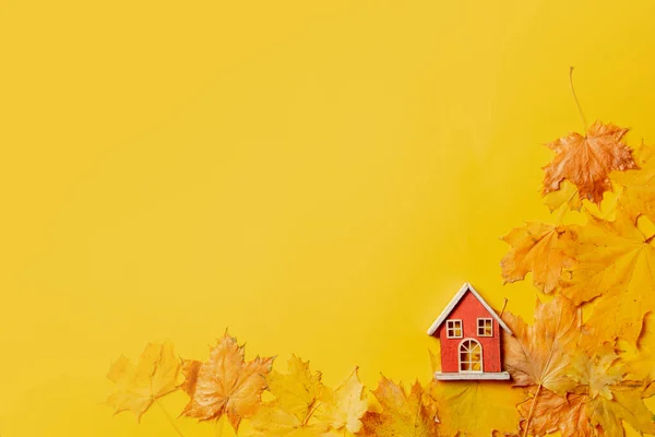 Kleines Spielzeughaus Und Ahornblätter Auf Gelbem Hintergrund Ansicht Von Oben — Stockfoto