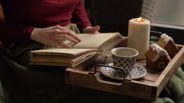 Yatakta kahve içen bir kadın. Kurabiye ve mumlu tepsi