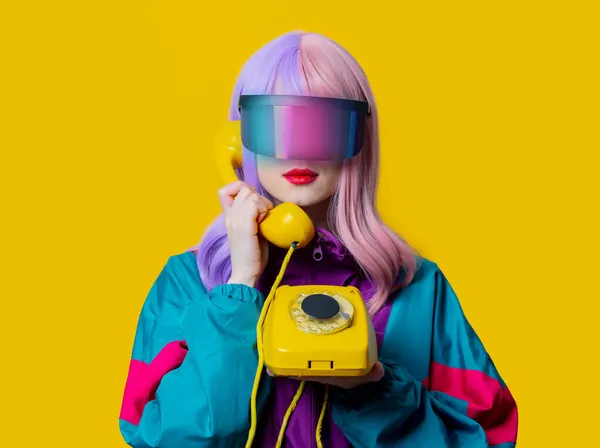 黄色の背景にダイヤル電話でVrメガネと90年代のスポーツスーツのスタイルの女性 — ストック写真