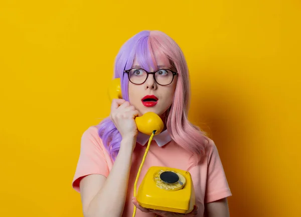紫の髪とピンクのドレスを持つ女の子は黄色の背景にダイヤル電話を保持 — ストック写真
