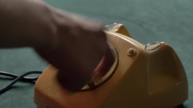 Kadın evdeki eski bir telefondan numarayı çeviriyor.