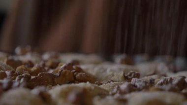 Kadın evdeki masada fındıklı turtaya şeker serpiyor.