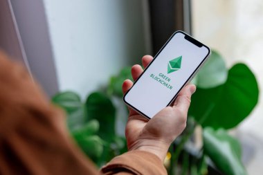 23 Kasım 2021 - Wroclaw, Polonya: Yeşil eko ethereum logolu iPhone 'u tutan adam. 2022 Yılı Trend