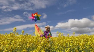 Baharda sarı kolza tohumu tarlasında LGBT gökkuşağı bayrağı taşıyan kadın