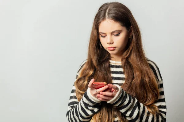 Vacker Flicka Randig Tröja Sms Ett Meddelande Sin Mobiltelefon Vit — Stockfoto