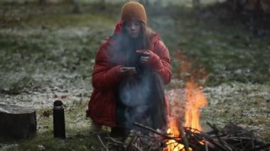 Kampta şenlik ateşinin yanında oturan kupalı genç kız.