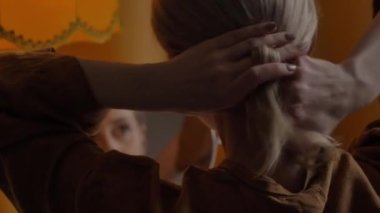 Orta yaşlı kadın aynanın yanındaki masada oturuyor ve yüz masajı yapıyor.