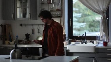 Mutfakta cep telefonu olan beyaz bir adam.