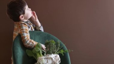 Küçük çocuk ağ torbasından taze dereotu yiyor.