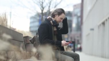 Polonya 'nın Wroclaw şehrinin bir caddesinde atkı ve siyah ceketli şık bir adam cep telefonu kullanıyor.