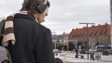 Wroclaw, Polonya 'da sokakta yürüyen akıllı telefon ve kulaklıklı şık bir adam.