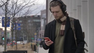 Wroclaw, Polonya 'da sokakta yürüyen akıllı telefon ve kulaklıklı şık bir adam.