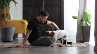 Adam evde bir köpeğin yanında sağlık için egzersiz yapmaya çalışıyor.