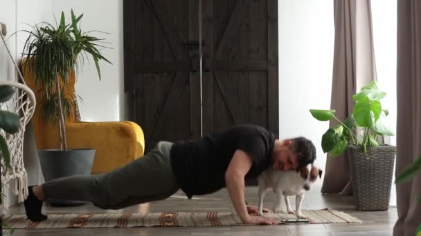 Mann Versucht Neben Hund Hause Für Die Gesundheit Trainieren — Stockvideo