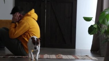 Evde köpek ve akıllı telefonla yerde yatan bir adam.