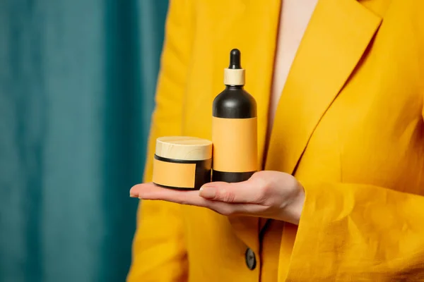 Sarı Ceketli Şık Kadın Kozmetik Şişe Tutuyor — Stok fotoğraf