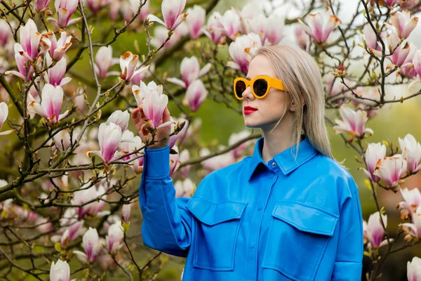 Piękna Blondynka Okularach Przeciwsłonecznych Niebieskiej Koszuli Obok Drzewa Magnolia Wiosną — Zdjęcie stockowe