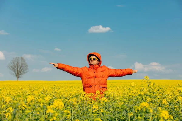 Kolza tarlasında turuncu ceketli şık bir adam.