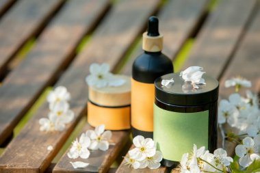 Kozmetik kavanozu, çiçek açan ağaç baharı bahçesindeki ahşap masada.