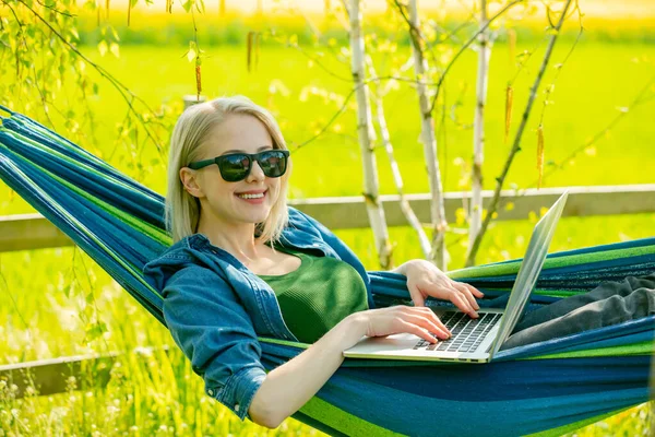 Hamaktaki kadın kırsal kesimdeki hamakta dizüstü bilgisayarla çalışıyor.