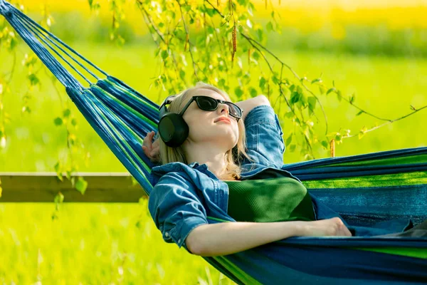 在农村 戴耳机的年轻女子在吊床上听音乐 — 图库照片