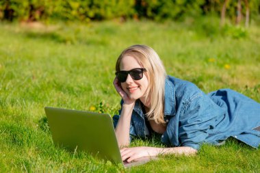 Bahçedeki çimlerin üzerinde bilgisayarı olan bir kadın