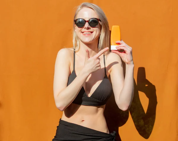 Girl Bikini Puts Sunscreen Her Body Orange Background — Stockfoto