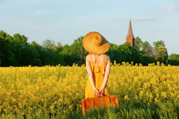 Stylish Girl Yellow Dress Suitcase Rapeseed Field Village Curch Background — 스톡 사진