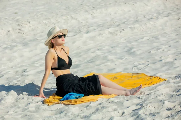 女性はビキニとリラックスしてビーチに座っています — ストック写真